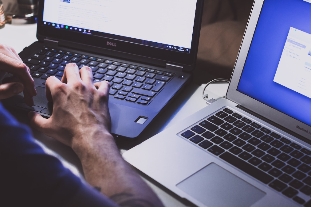 Person working on two different laptops